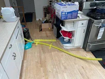 Drying hoses running under kitchen cabinets on a wet hardwood floor