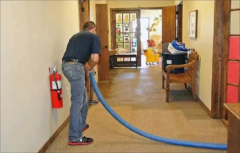 Technician running an extraction hose through a wet hallway in Auburn