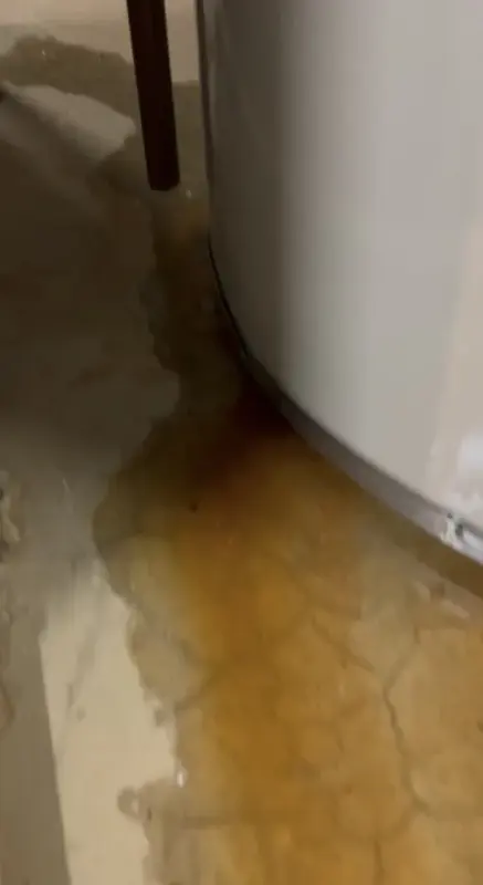 Rust-stained water spreading from the base of a failing tank water heater
